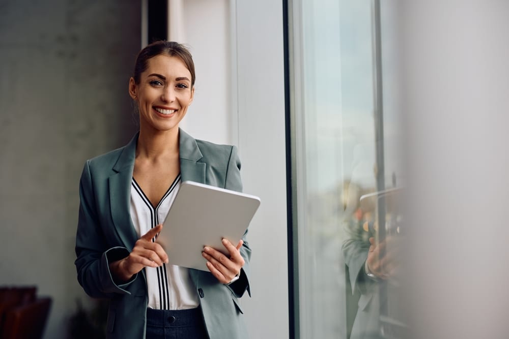 A woman standing holding a laptop with a beautiful smile, real estate