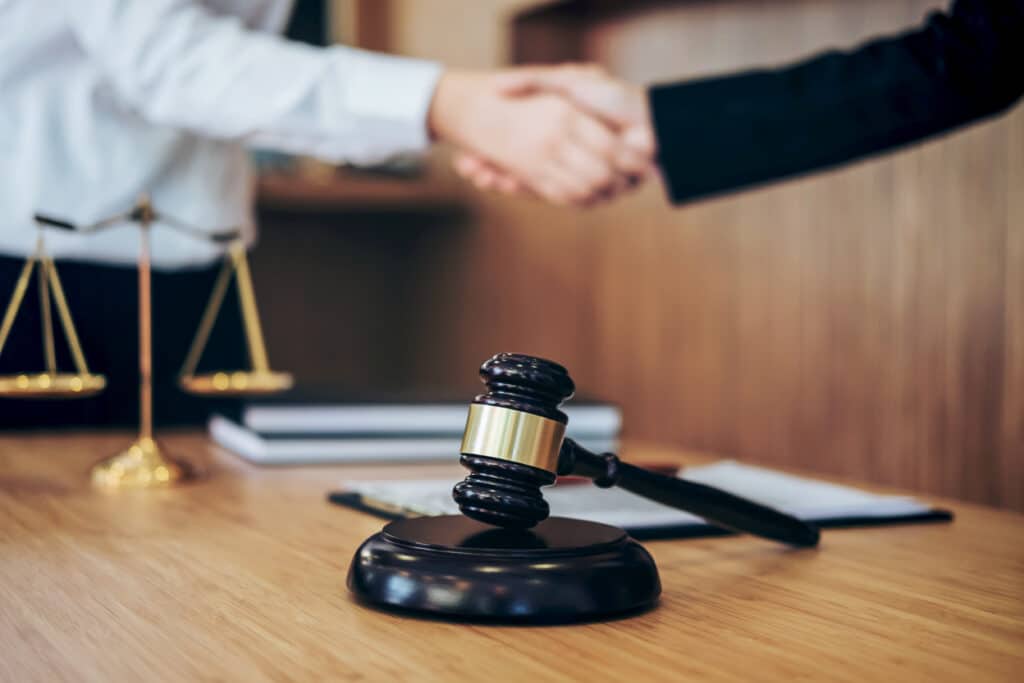 cropped-image-paralegal-client-shaking-hands-with-gavel-table