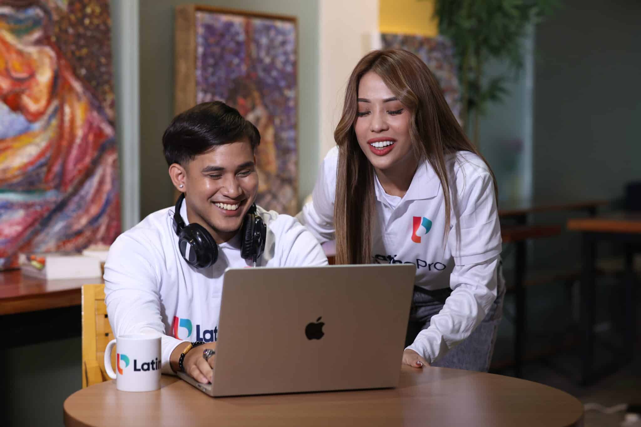 Two smiling colleagues collaborating on a laptop, showcasing effective teamwork for a virtual operations assistant manager role
