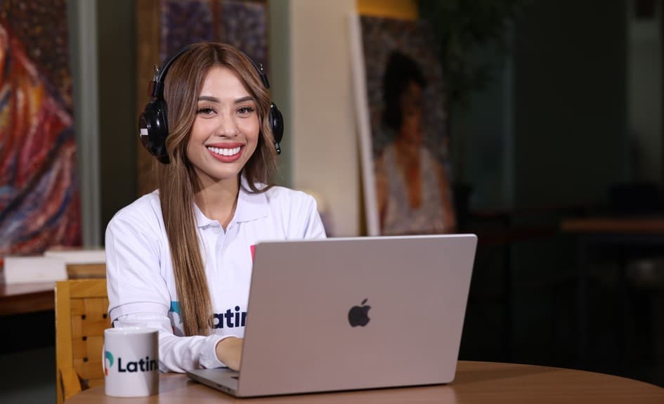 A smiling woman wearing headphones and a white polo shirt uses a laptop, representing efficient and accessible Virtual Estimator Services