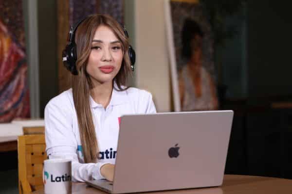 A woman with headphones on her laptop, working on virtual receptionist jobs for Latino.