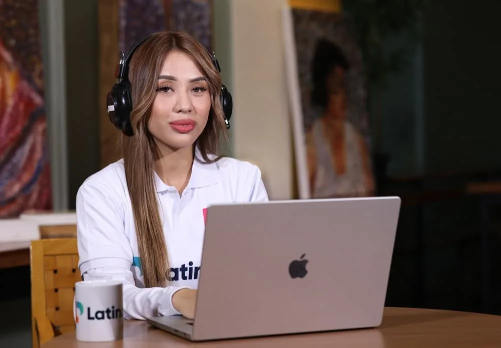 A woman with headphones on her laptop, working on virtual receptionist jobs for Latino.