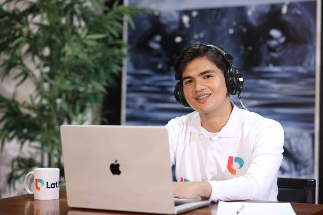 Man smiling at laptop with headphones, ideal for explaining what does contingent mean in real estate.