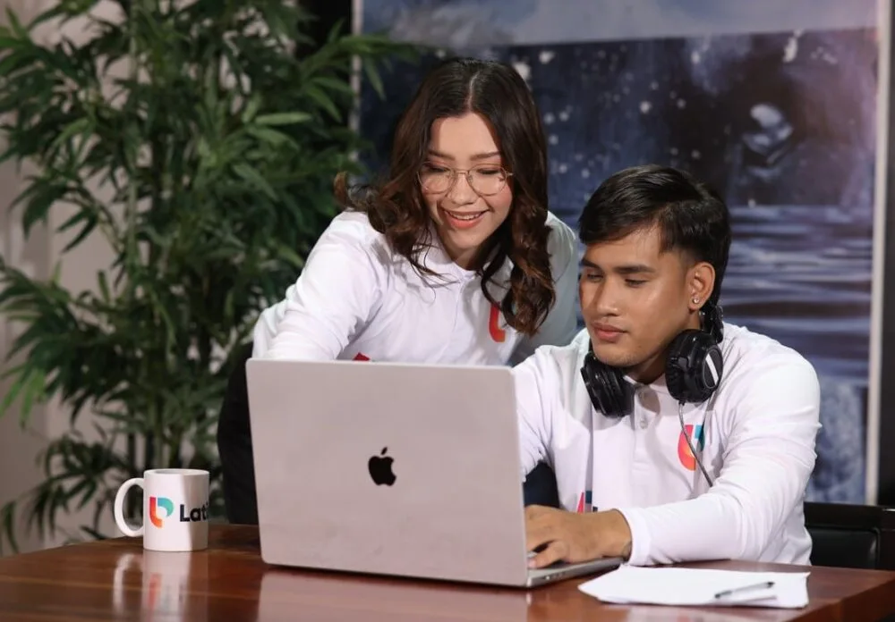 Two professionals working together on a laptop, providing virtual receptionist services.