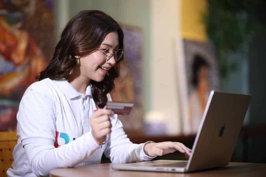 Woman with credit card and laptop, exemplifying tasks within an executive assistant job description.
