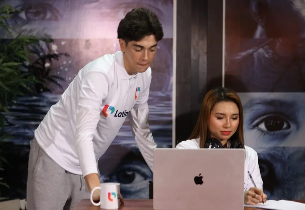 A legal research assistant oversees a colleague's work on a laptop and notepad