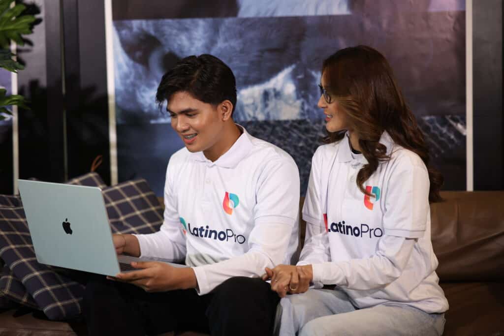 A man and woman with LatinoPro polos collaborate on a laptop, showcasing essential administrative assistant hard skills.