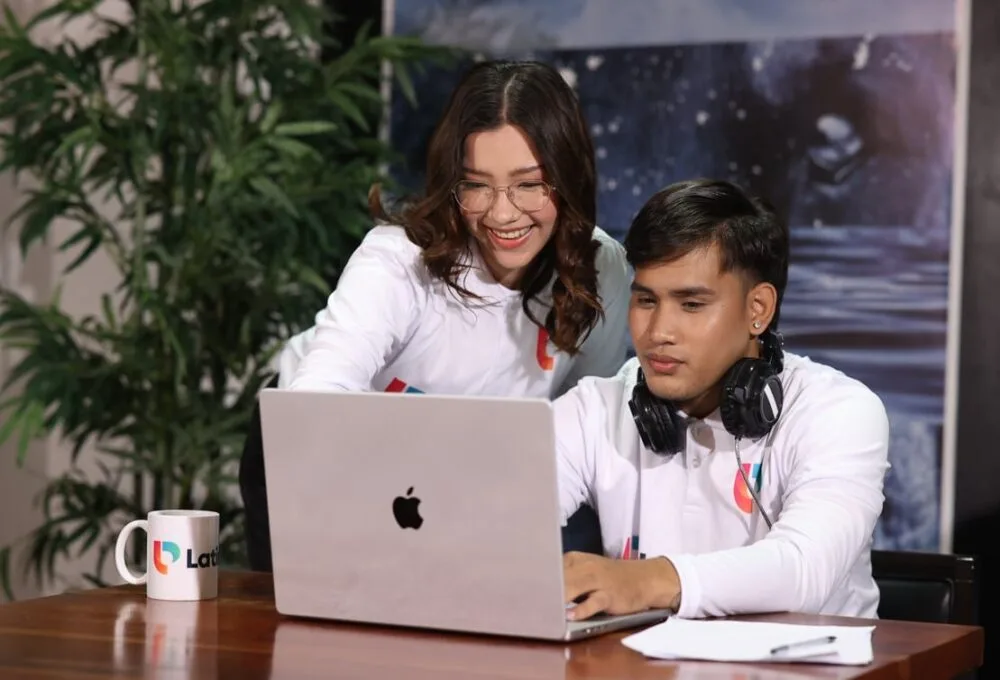 A smiling professional legal research assistant helps a colleague on a laptop