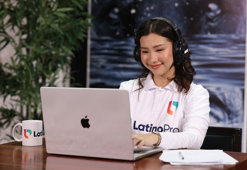 A smiling woman wearing headphones works on a laptop. Find out more about becoming a legal transcriptionist with us