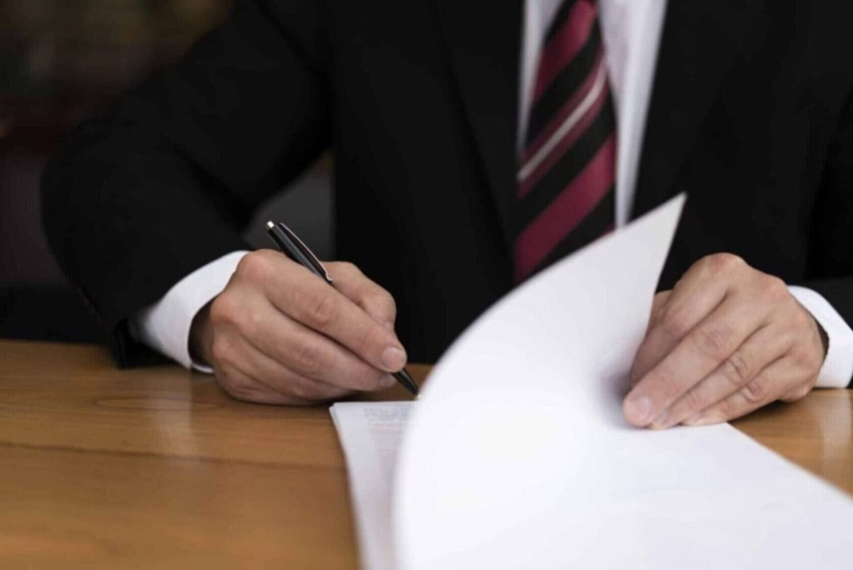 Business professional signing documents, emphasizing the importance of legal assistant certification for career growth.