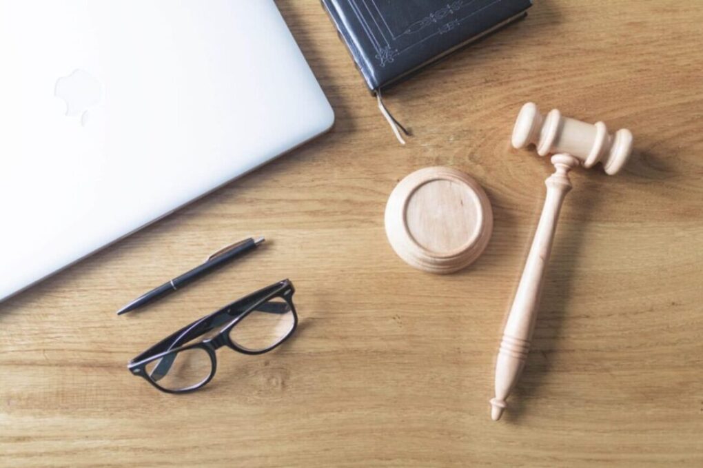 Desk with laptop, gavel, notebook, and glasses representing outsourced legal intake support for law firms.