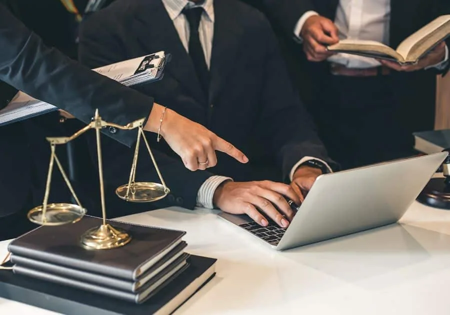 Law office team working with laptop, legal books, and scales, highlighting career opportunities in paralegal assistant jobs.