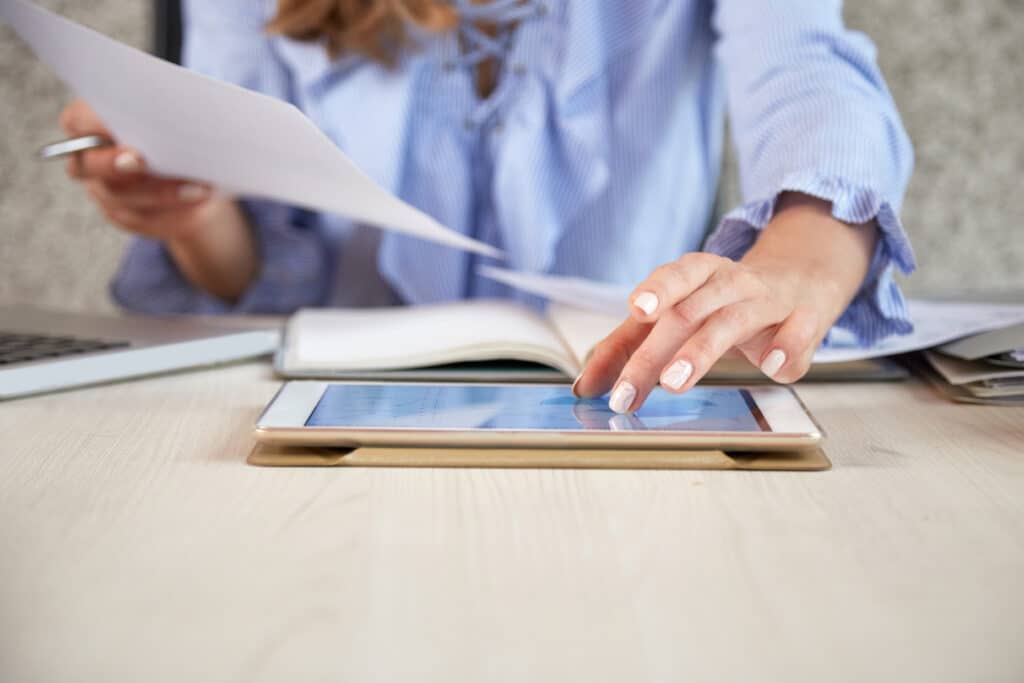 Professional woman using tablet and papers showing How Do Document Review Specialists Virtual Assistant Operate In Law Firms.