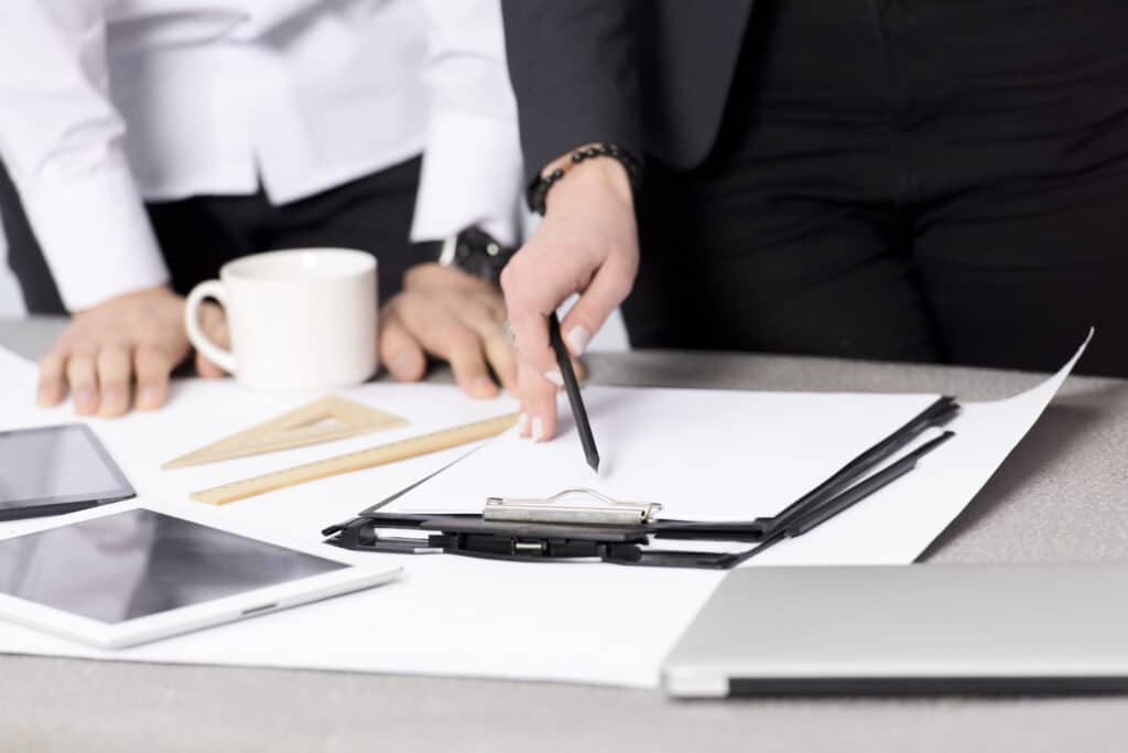 Professionals reviewing documents on clipboard, discussing outsourced legal intake with office tools on desk.