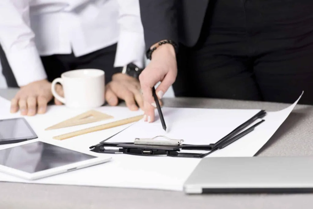 Professionals reviewing documents on clipboard, discussing outsourced legal intake with office tools on desk.