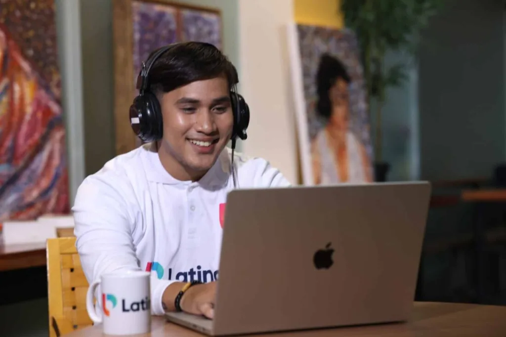 Smiling man with headphones using laptop, illustrating how to become a legal transcriptionist in a remote work setting.