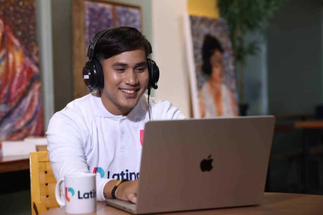 Smiling man with headphones using laptop, illustrating how to become a legal transcriptionist in a remote work setting.