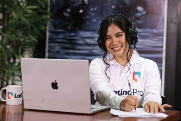Smiling woman with headphones and a mug looking at a laptop. Become a legal assistant from home with our program