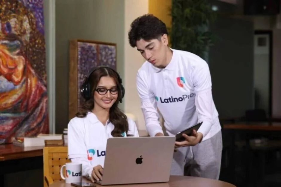 Two colleagues in LatinoPro shirts collaborate on laptop, showcasing online legal assistant training in a professional setting.