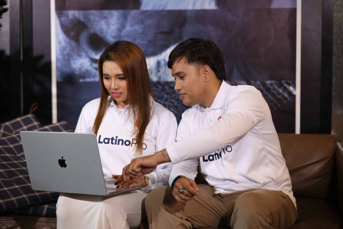 Two professionals in LatinoPro shirts collaborating on a laptop discussing legal transcriptionist work.