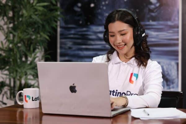 What does it take to be a legal assistant? A woman smiles while working on a laptop with a LatinoPro mug beside her