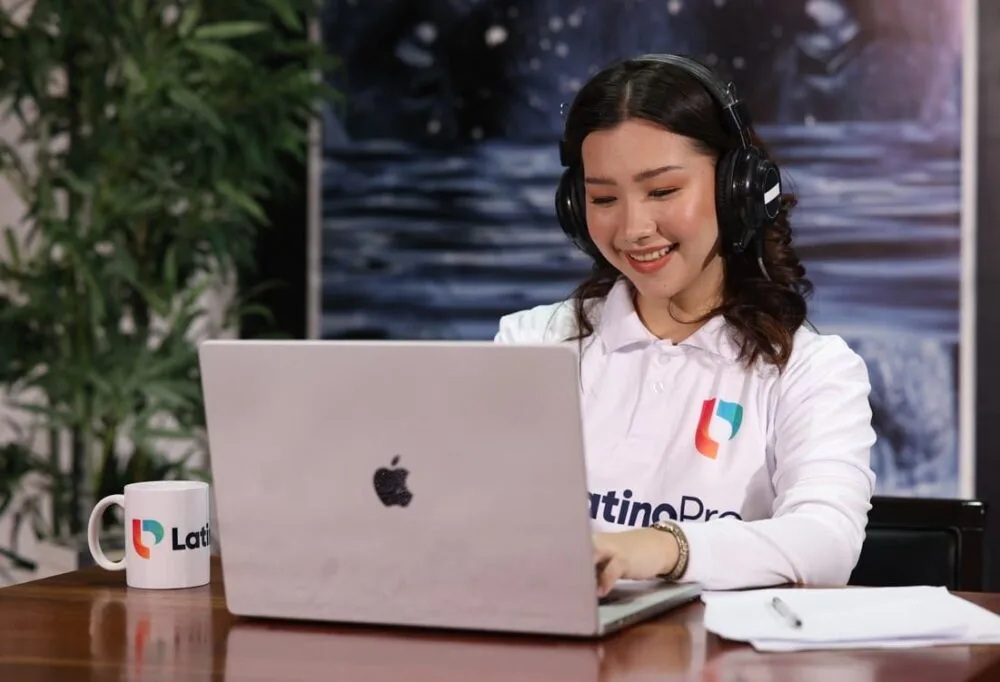 What does it take to be a legal assistant? A woman smiles while working on a laptop with a LatinoPro mug beside her
