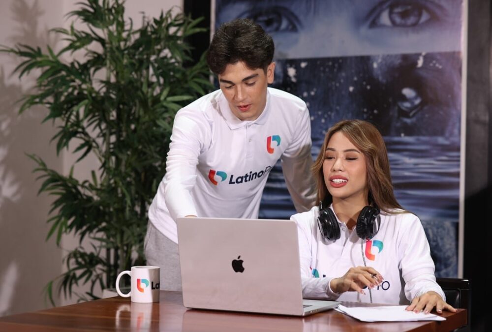 A man and woman work together on a laptop in an office
